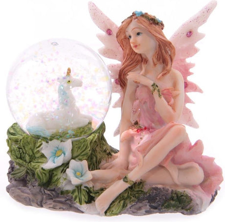 Blumenfee sitzt mit einer Schneekugel